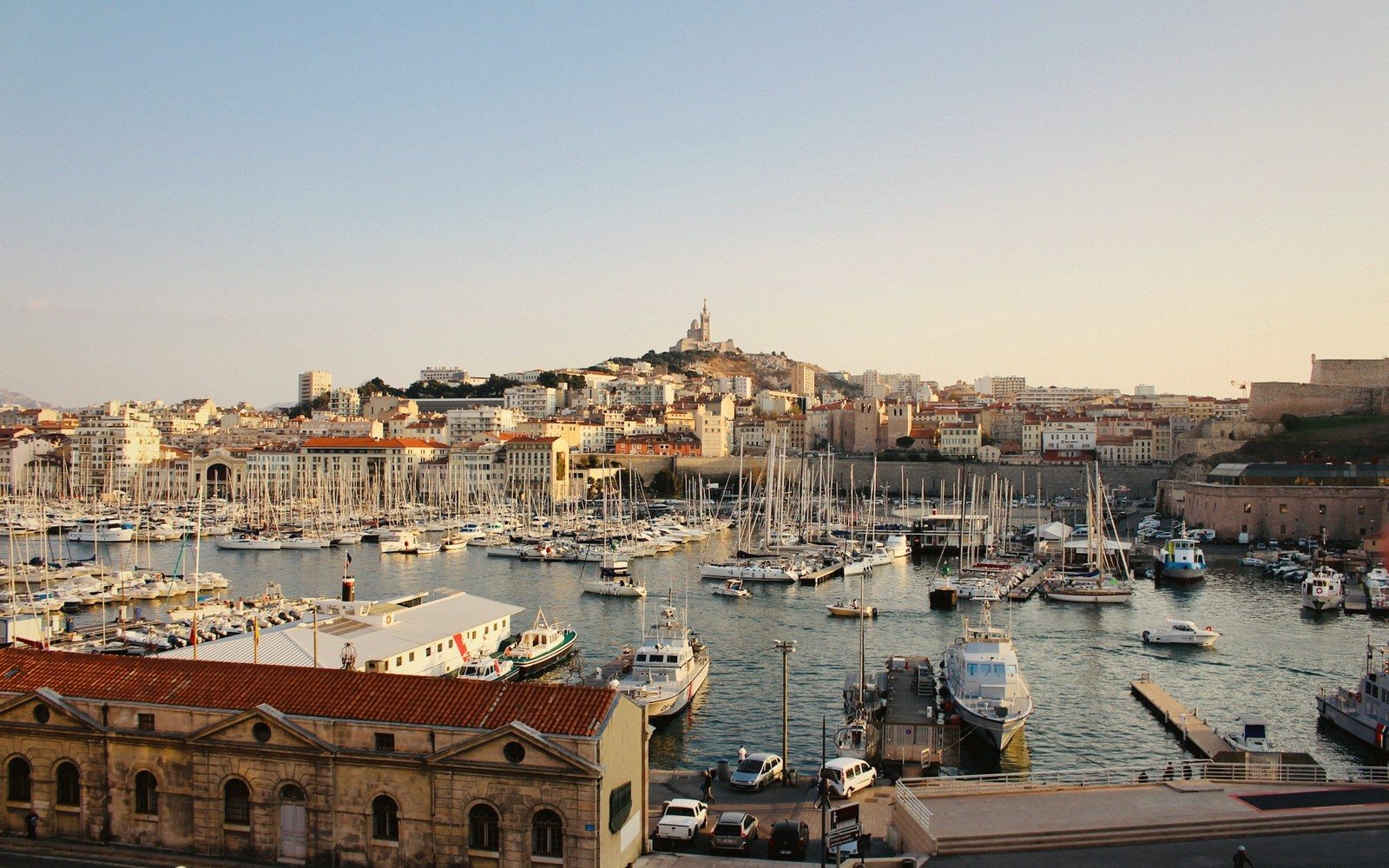 Sailboats crowd Marseille's Vieux Port with Notre-Dame de la Garde basilica on the hilltop beyond